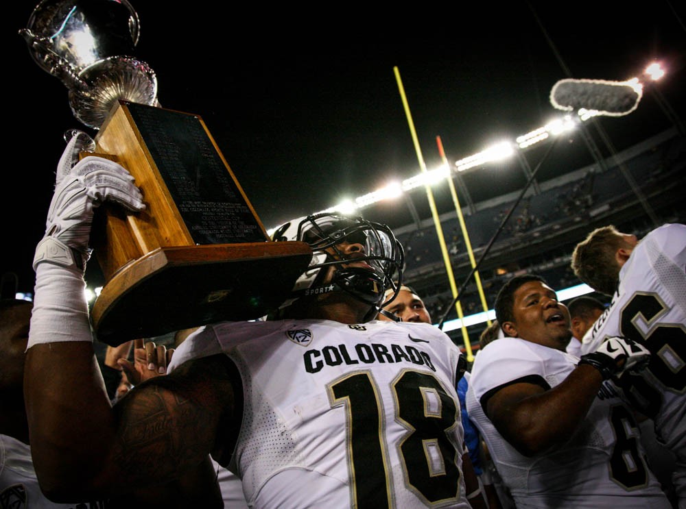 George Frazier (18) holds the trophy high after defeating the Rams Saturday night 27-24 during the Rocky Mountain Showdown that went into nail-biting over-time. (Danny Anderson / CU Independent)