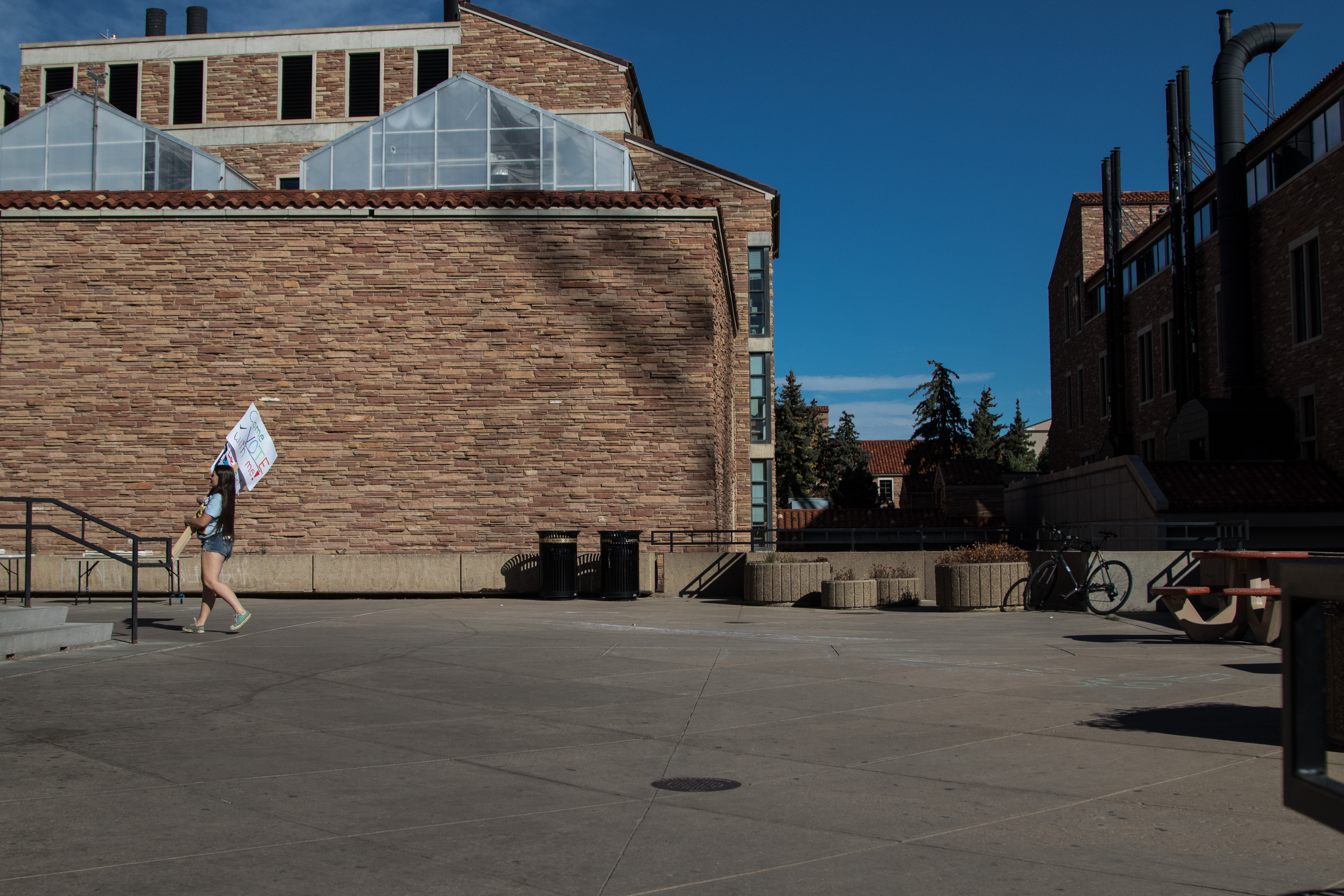 In a rare empty moment a Democratic supporter carries voting signs to the UMC fountain area. (Jackson Barnett/CU Independent)