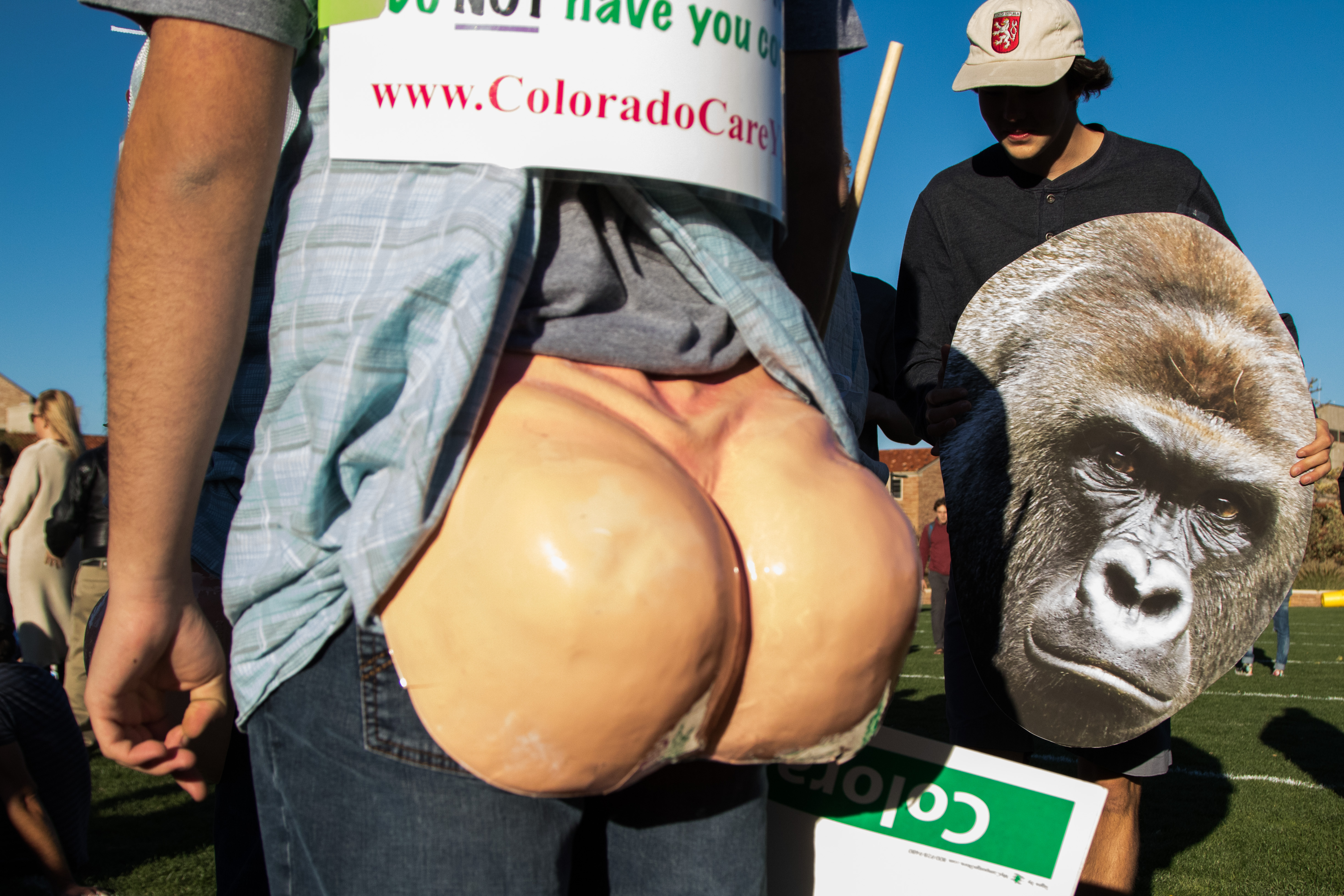 Colorado Car supporters wear fake butts to show their support of amendment 69 while a student holds a Harambe poster on Farrand Field. Harambe, the gorilla killed in the Cincinnati zoo, became a rallying cry for many at CU during the election. More so as a joke than for animal rights, Harambe was remembered through signs and even themed parties. (Jackson Barnett/CU Independent)