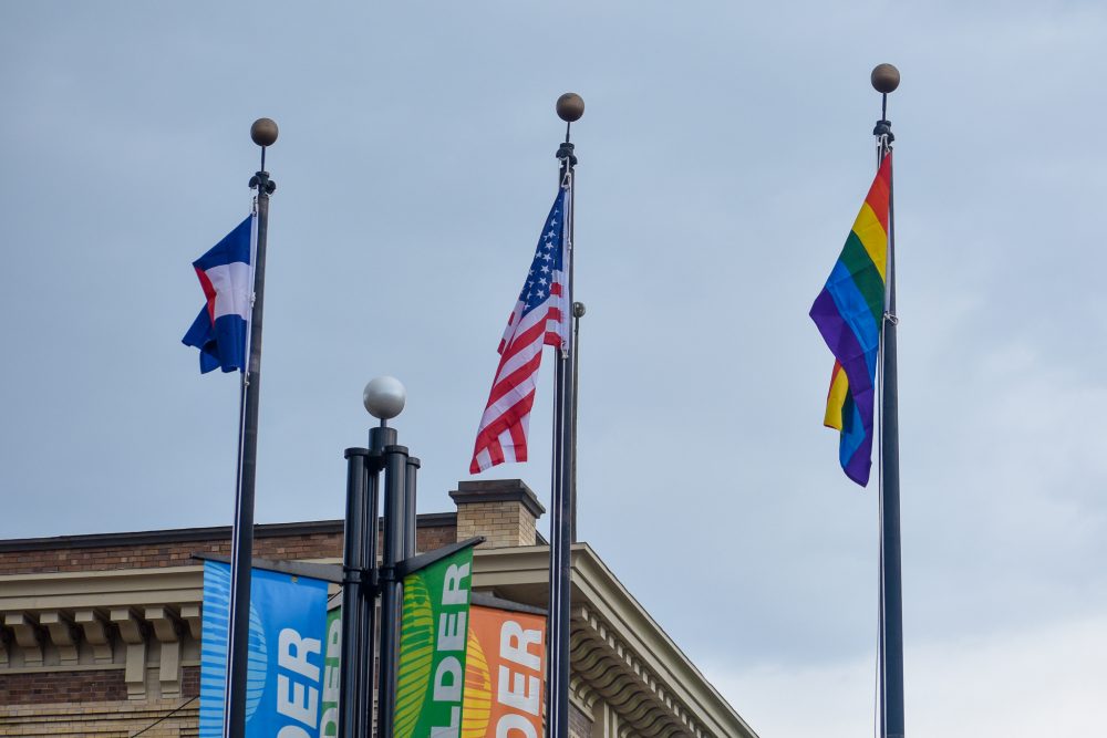 Pride flag hoisted alongside American flag and Colorado flag on Pearl Street.